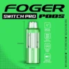 Sour apple ice pod for the Foger Switch Pro with its clear 19mL tank next to the magnetic power bank dock